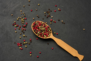 Mixed dry peppercorns in a wooden spoon on a black table, top vi, a Food & Drink Photo by ndanko