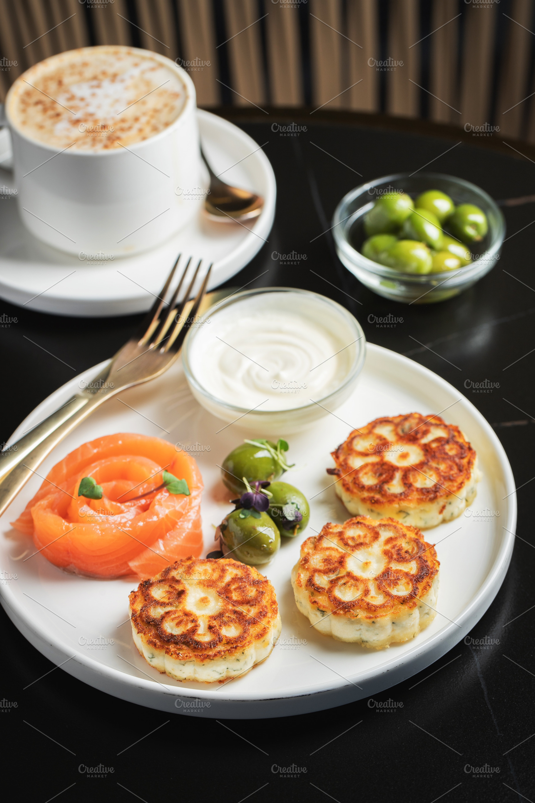 Savory Syrniki with Smoked Salmon, Olives and Sour Cream on White Plate, a Food & Drink Photo by Budarinphoto
