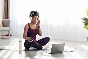 Athletic black woman with headset sitting in front of laptop