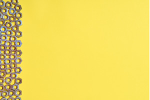 Vertical metal nuts border on yellow, an Industrial Photo by Gladkov photography