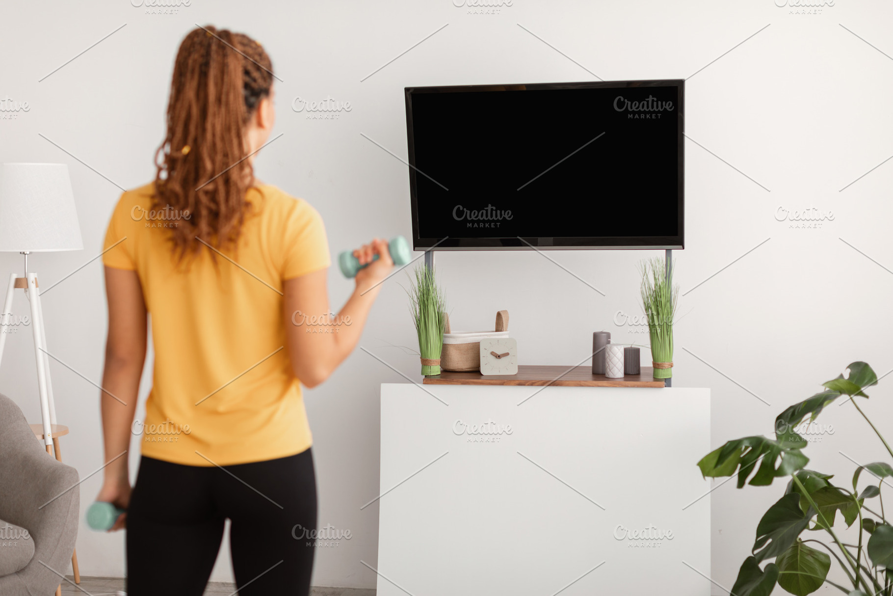 Lady Exercising With Dumbbells Watching TV At Home, Rear View, a Photo by Prostock-Studio