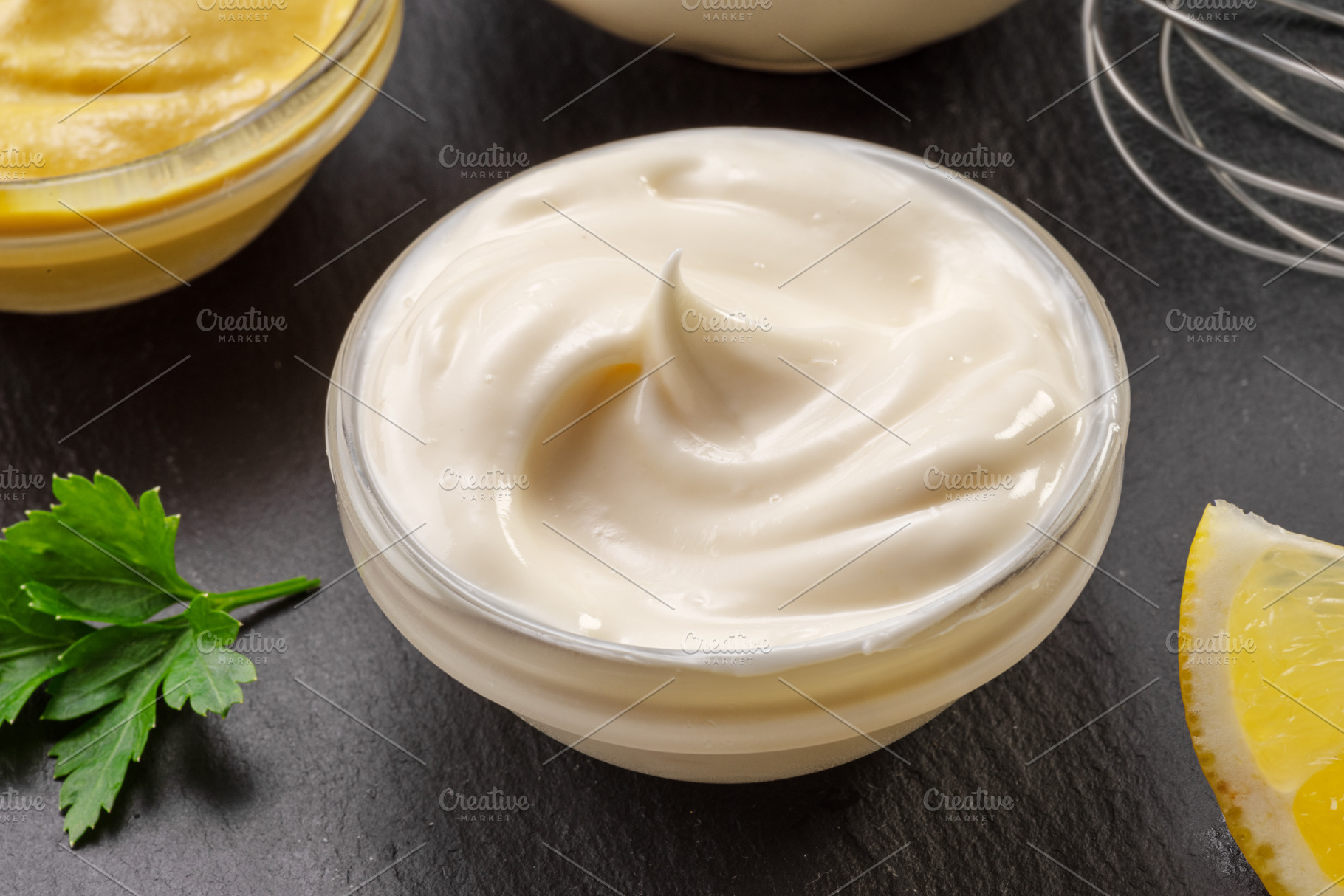 Glass bowl of homemade mayonnaise on black stone slate serving p, a Food & Drink Photo by Volff