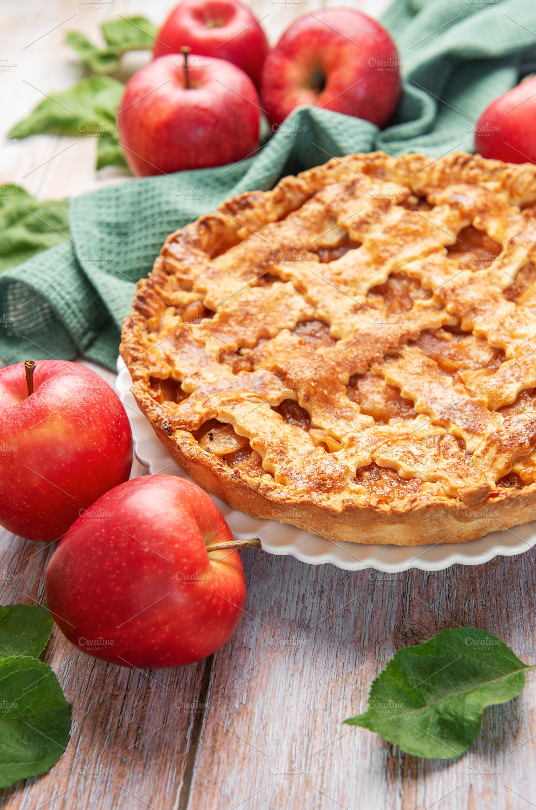 Freshly baked apple pie surrounded by ripe red apples and green, a Food & Drink Photo by Olena Rudo