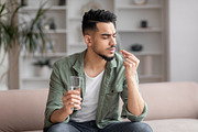 Sad young arab man with beard in casual sits on sofa with glass of water and lo, a Photo by Prostock-Studio (Thumbnail 1 of 2)
