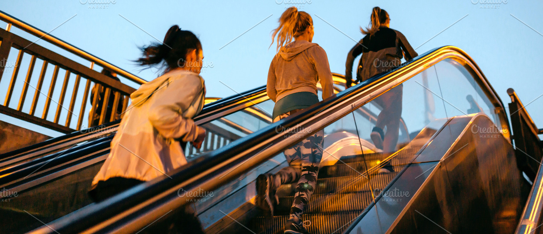 Women friends training running up escalator in city on sunset, a Sports & Recreation Photo by davidpereiras