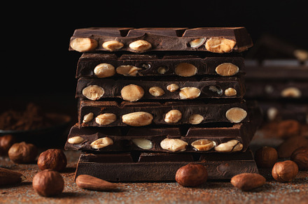 Dark and milk chocolate with nuts on a dark background sprinkled with cocoa pow, a Food & Drink Photo by Budarinphoto