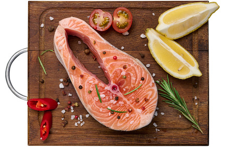 Raw salmon steak on a wooden cutting board, lemon slices, spices, a Food & Drink Photo by ndanko