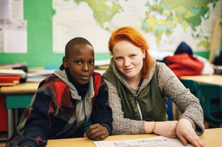 African refugee boy and his school teacher are in a classroom, a Photo by zakiroff