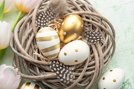 Nest with Easter eggs painted golden colors on a green wooden ba, a Holiday Photo by Olena Rudo