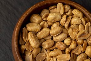 roasted peanuts in a wooden round bowl, crunchy peanuts without shells on a bla, a Photo by rsoollAI