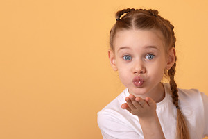 Adorable young girl in white t-shirt blowing a kiss with playful, a Person Photo by Ales Munt