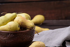 Ripe yellow green pears in a brown ceramic bowl on a wooden tabl, a Food & Drink Photo by ndanko