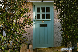 Green cottage door with roof and wooden gate, providing privacy, a Photo by Studio ANNA