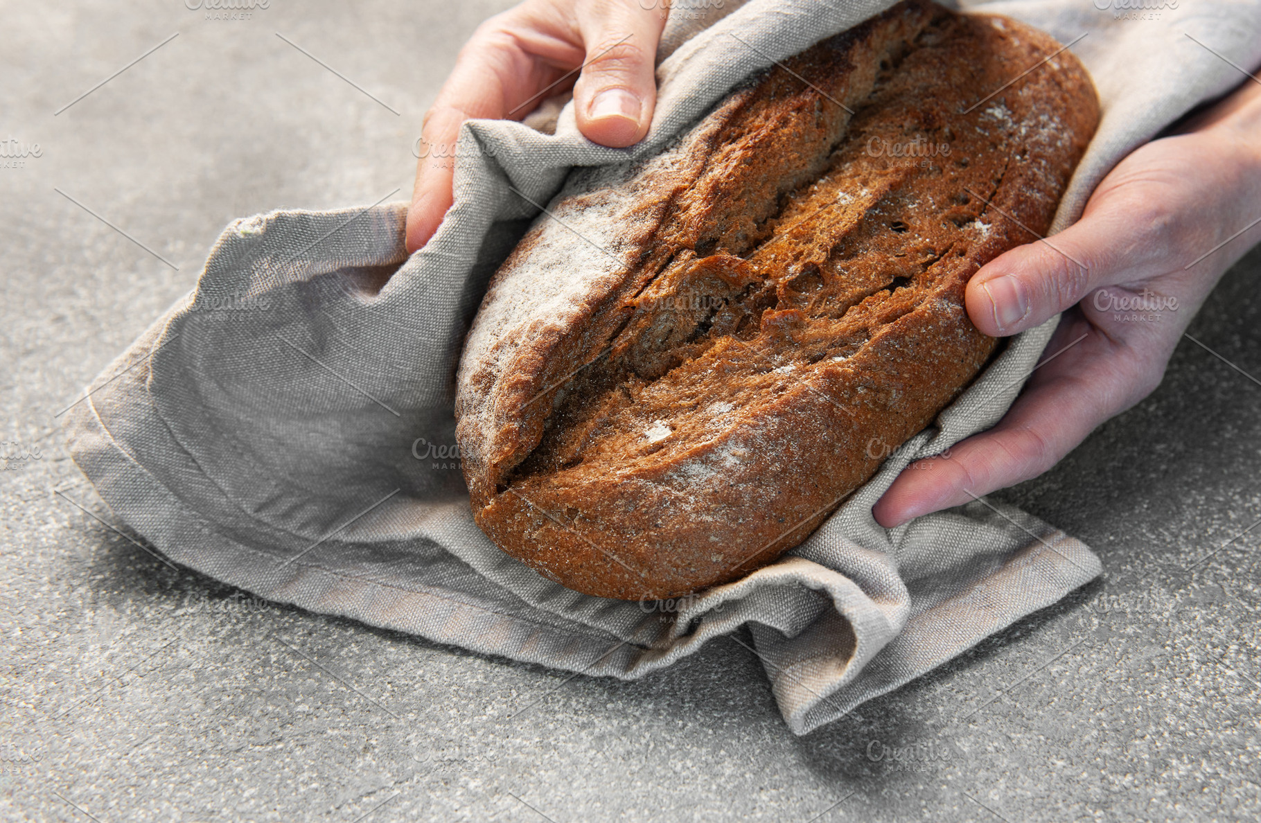 Hands holding freshly baked artisan rye bread, a Food & Drink Photo by Olena Rudo