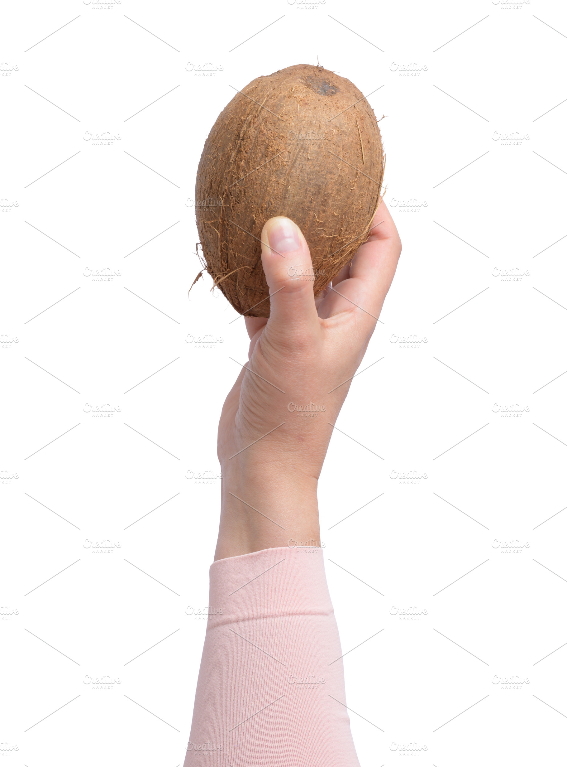 A woman's hand in pink clothes holds a whole brown coconut, a Food & Drink Photo by ndanko
