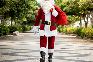 Santa Claus walking outdoors carrying large Christmas gift sack, a Person Photo by etorres69