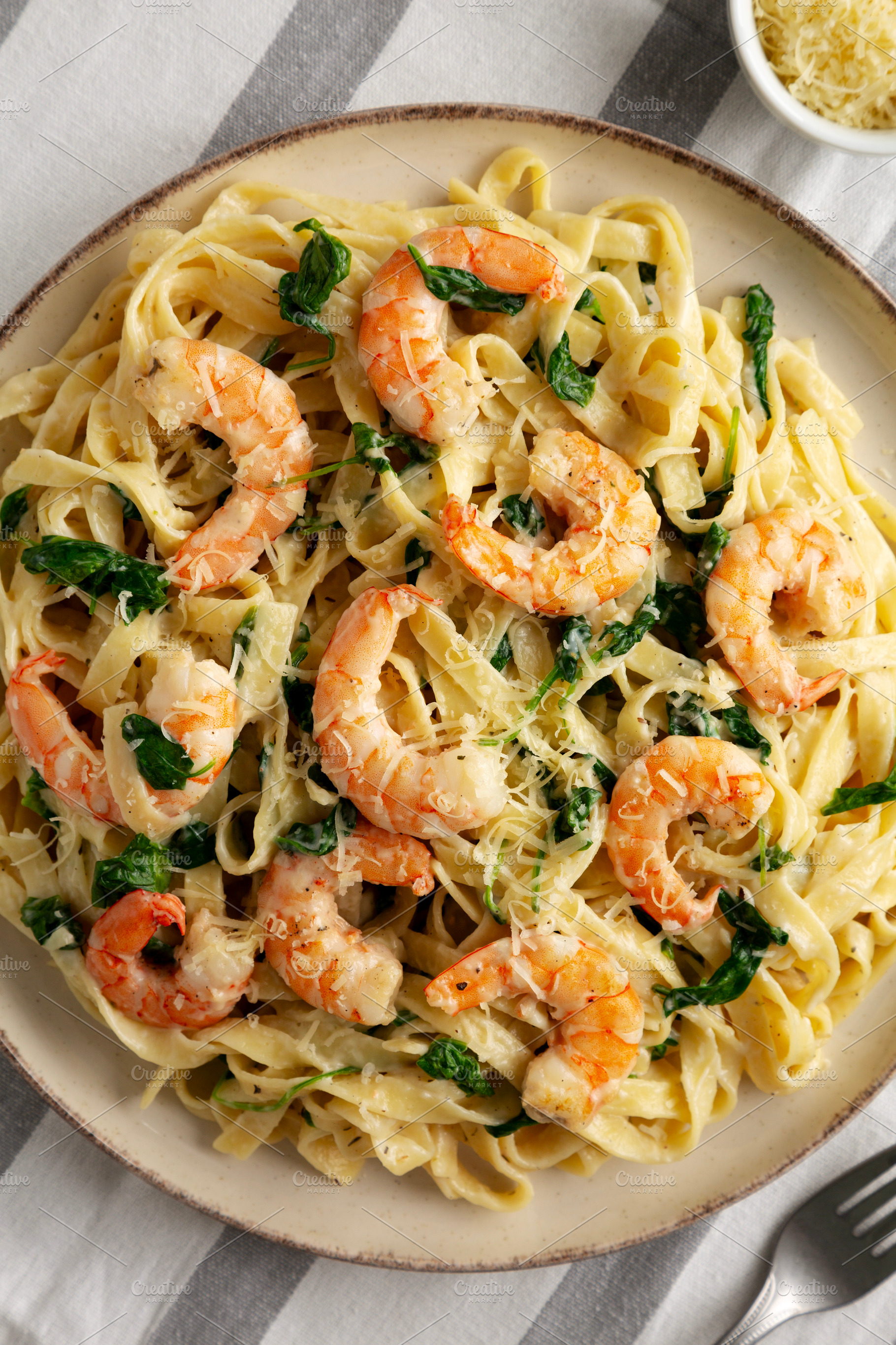 Homemade Creamy One-Pot Spinach Shrimp Pasta on a Plate, top vie, a Food & Drink Photo by LiudmylaChuhunova