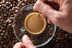 Hands stirring freshly brewed coffee over pile of coffee beans, a Food & Drink Photo by Davizro's Market