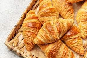 Freshly baked croissants resting on a wicker tray, a delightful, a Food & Drink Photo by Olena Rudo