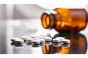 White pills reflected on a glossy, a Health & Medical Photo by Igor Tichonow