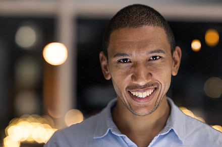 Business man portrait, smile and corporate worker ready for financial and accounting work at night. Company vision and happiness of a black man smile about finance growth in a modern office, a Photo by Peopleimages.com