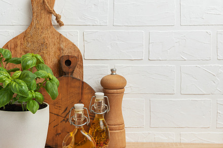 Fresh basil, olive oil, pepper mill and cutting boards resting o, a Food & Drink Photo by Olena Rudo