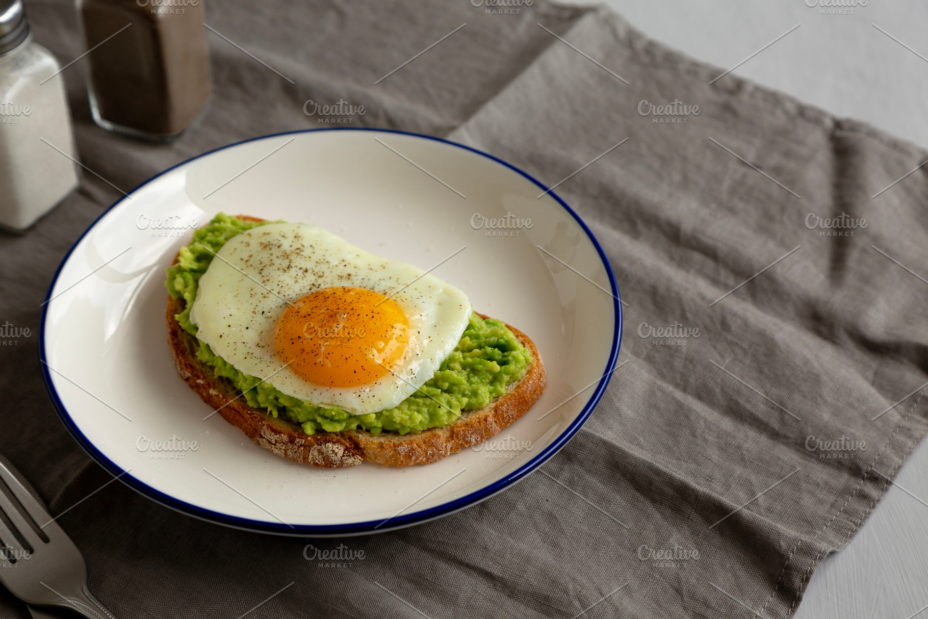 Homemade Avocado Toast with Egg on a Plate, side view. Copy spac, a Food & Drink Photo by LiudmylaChuhunova