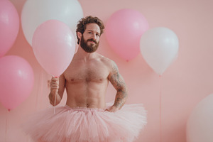 Man in a tutu holds pink balloon, a Photo by Beautiful things