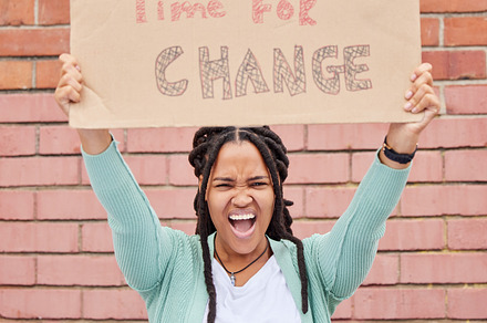 Protest, change and portrait of black woman with voice for human rights, gender equality and racism on brick wall. USA youth, gen z person or student with cardboard sign, freedom of speech and angry, a Photo by Peopleimages.com