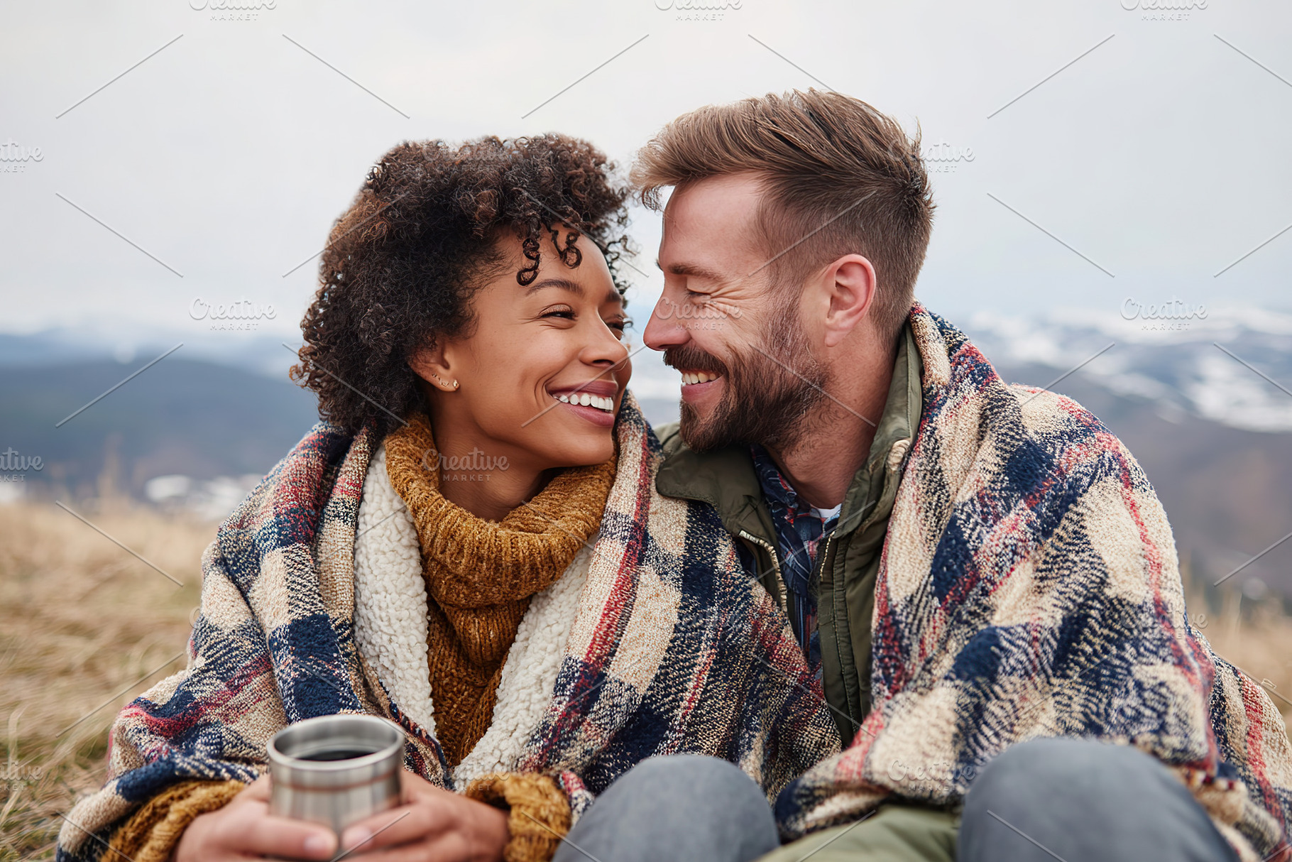 Couple enjoys a cozy moment wrapped in blankets on a mountain hillside during w, a Photo by AlyaAnd