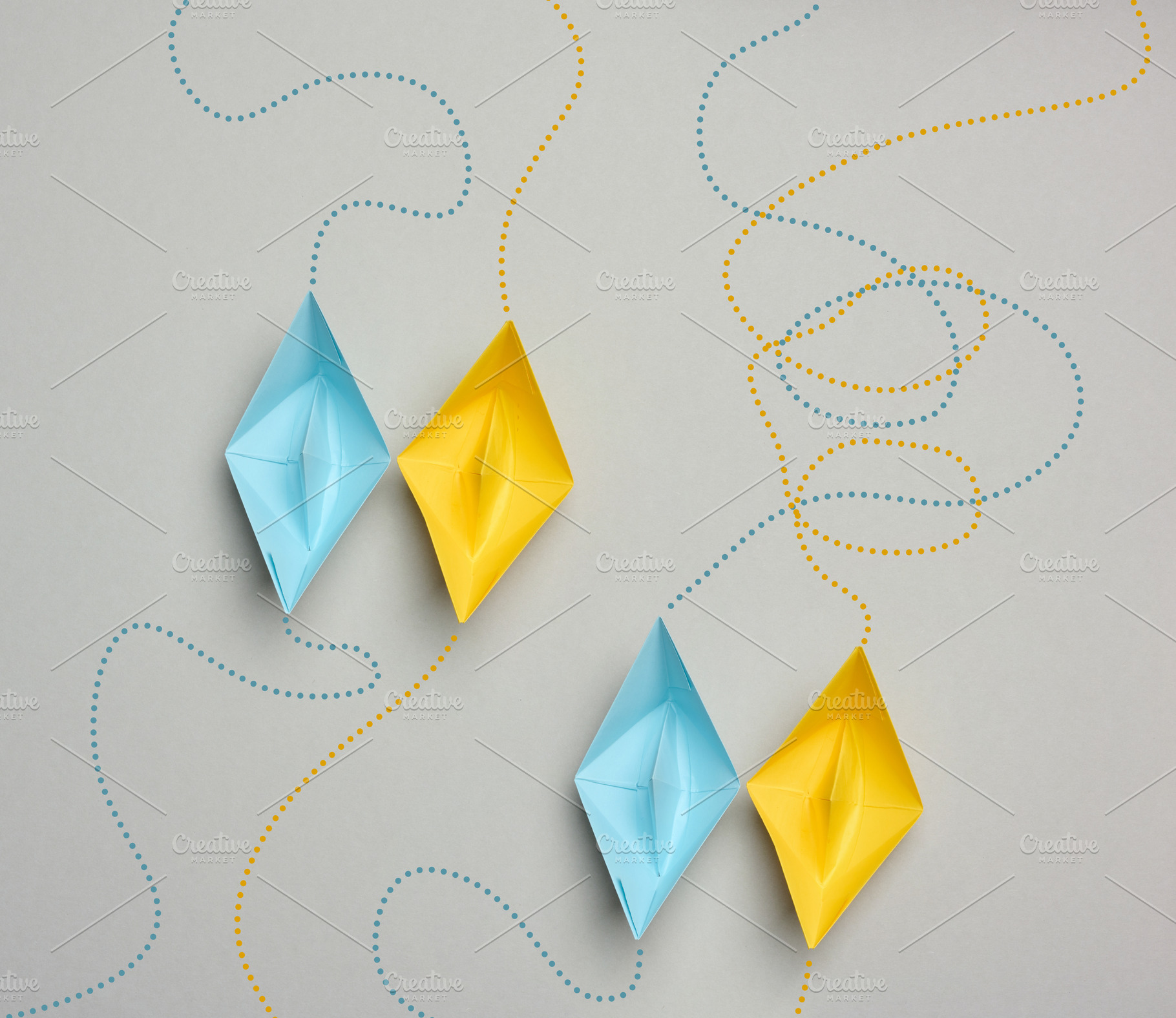 Blue and yellow paper boats sailing in pairs along dotted route, a Business Photo by ndanko