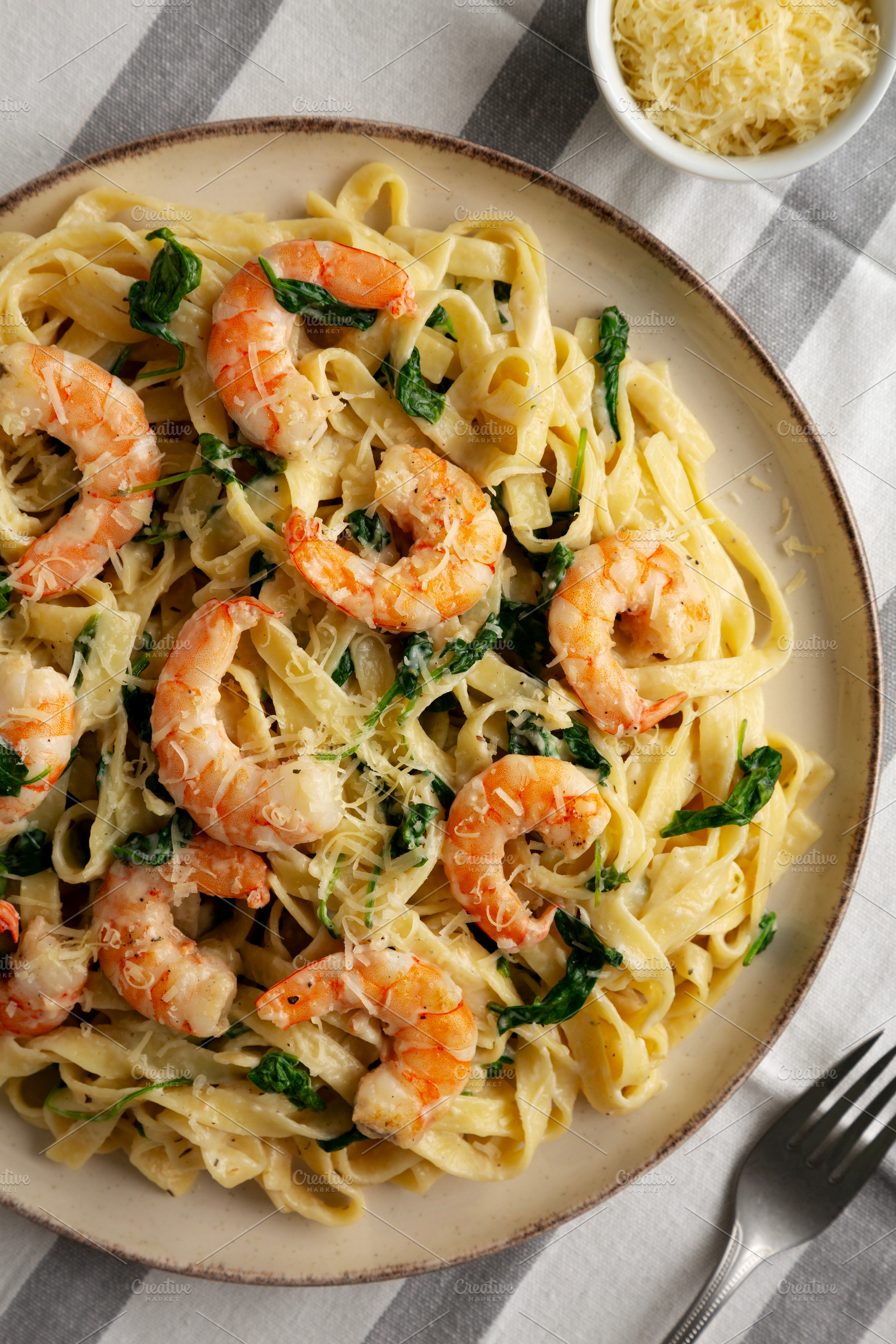 Homemade Creamy One-Pot Spinach Shrimp Pasta on a Plate, top vie, a Food & Drink Photo by LiudmylaChuhunova
