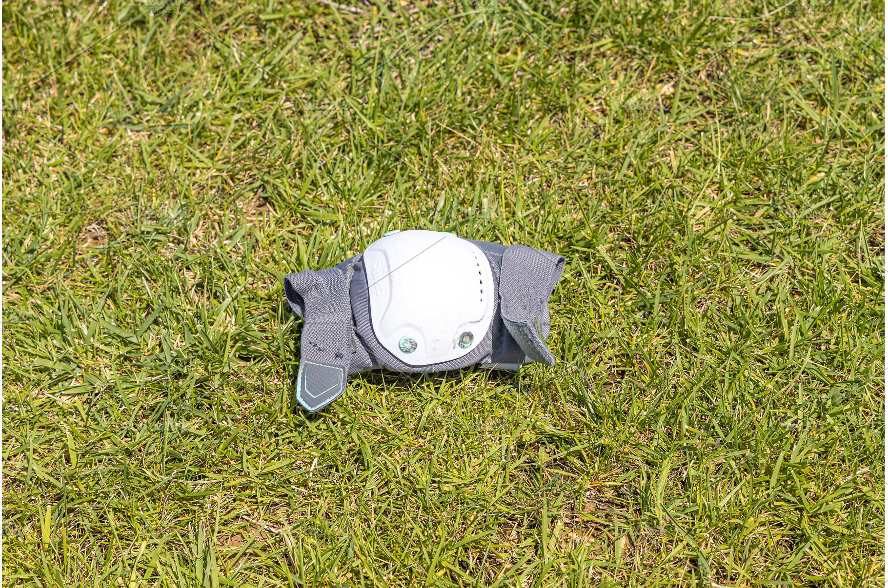 A gray elbow pad on the green grass, a Sports & Recreation Photo by Illustrations&photos
