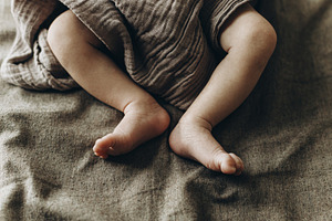 Adorable little baby feet close up in blanket on brown bed. Adop, a Person Photo by Sonjachni