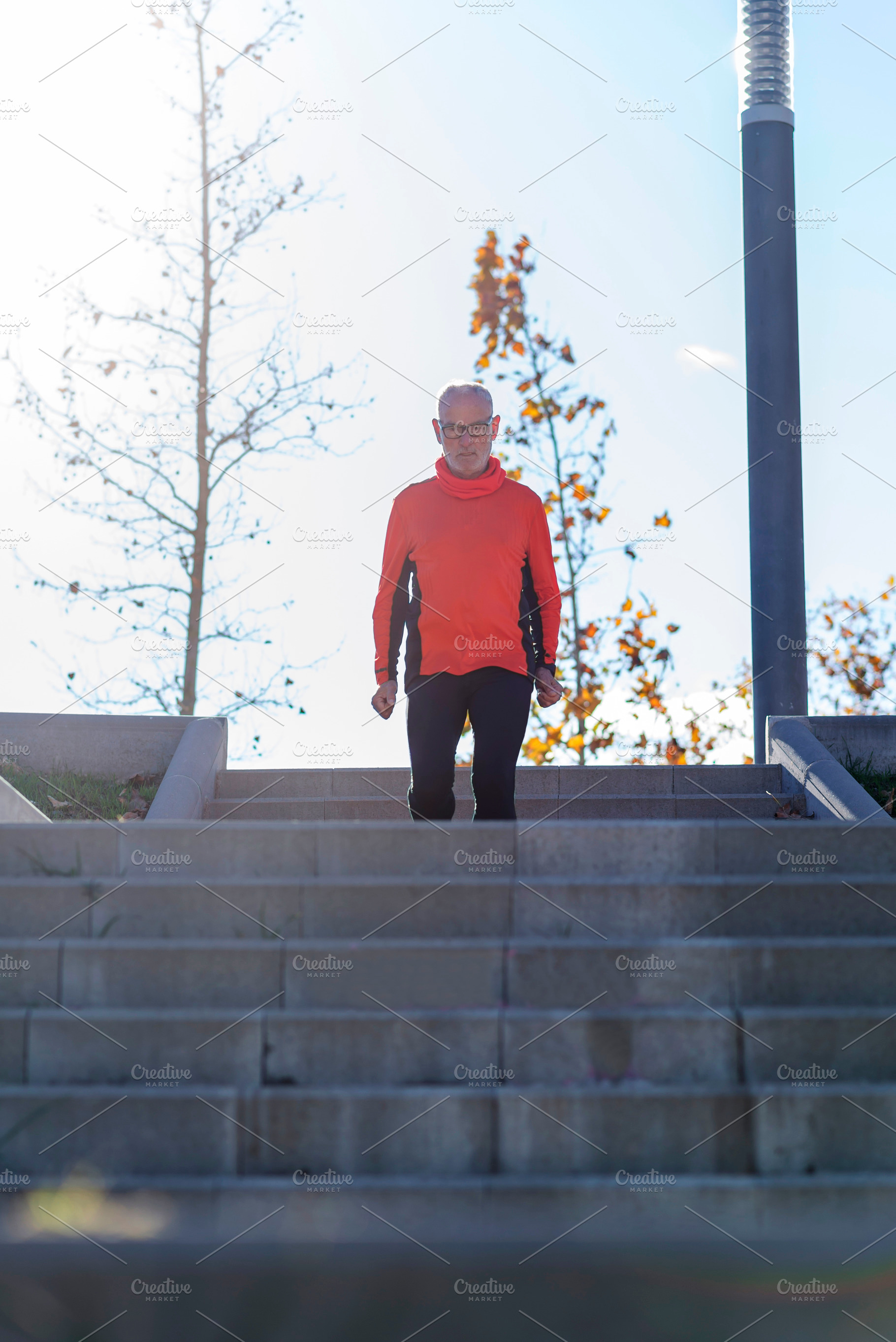 Senior man walking down stairs in a sunny outdoor park, a Sports & Recreation Photo by RF Images