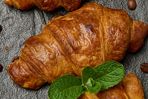 Golden croissants lined up on a dark stone board with a sprig of, a Food & Drink Photo by ndanko