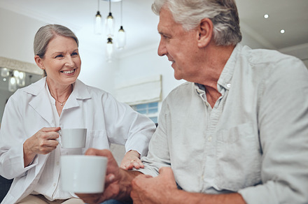 Coffee, morning and love with a senior couple drinking a beverage together in the living room of their retirement home. Tea, relax and talking with a mature man and woman bonding with a drink, a Photo by Peopleimages.com
