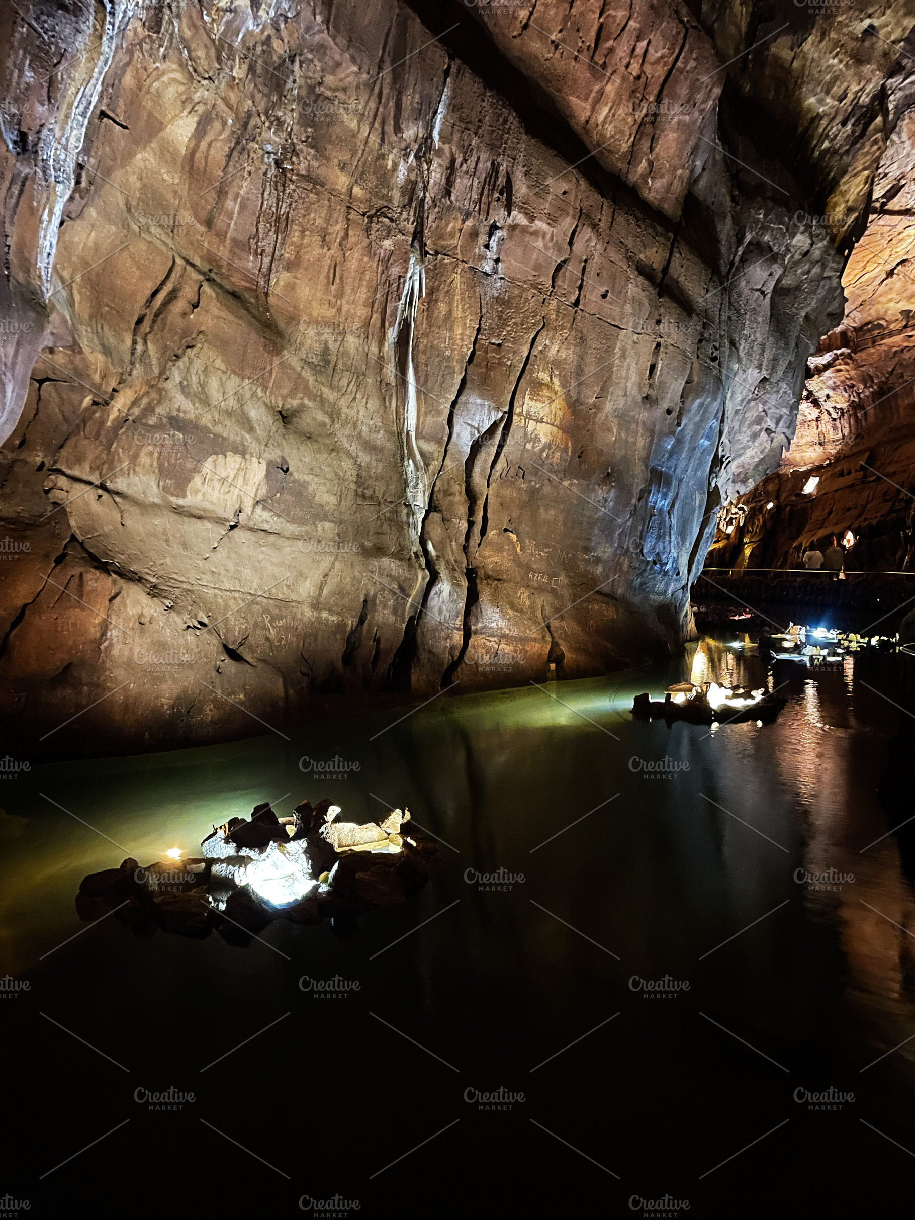 Scenic illuminated cave with water and rock formations in Mira de Aire, Portuga, a Photo by AS photostudio
