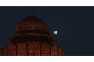 Full moon rising behind illuminated, an Architecture Photo by Our Amazing World