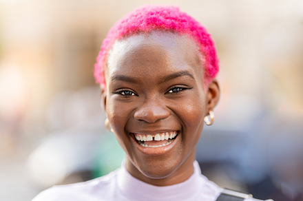 African woman with short pink hair smiling, a Person Photo by Iván Moreno STOCK PHOTO