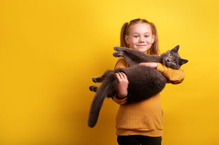 Smiling young girl in mustard sweater holding a large fluffy gra