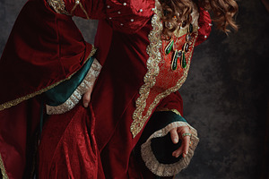 tired medieval queen in red dress with crown having backache, a Person Photo by Alliance Images