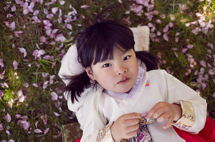 Korean girl child in a national costume lies on the back in a garden with cherr, a Person Photo by SaulichPhoto