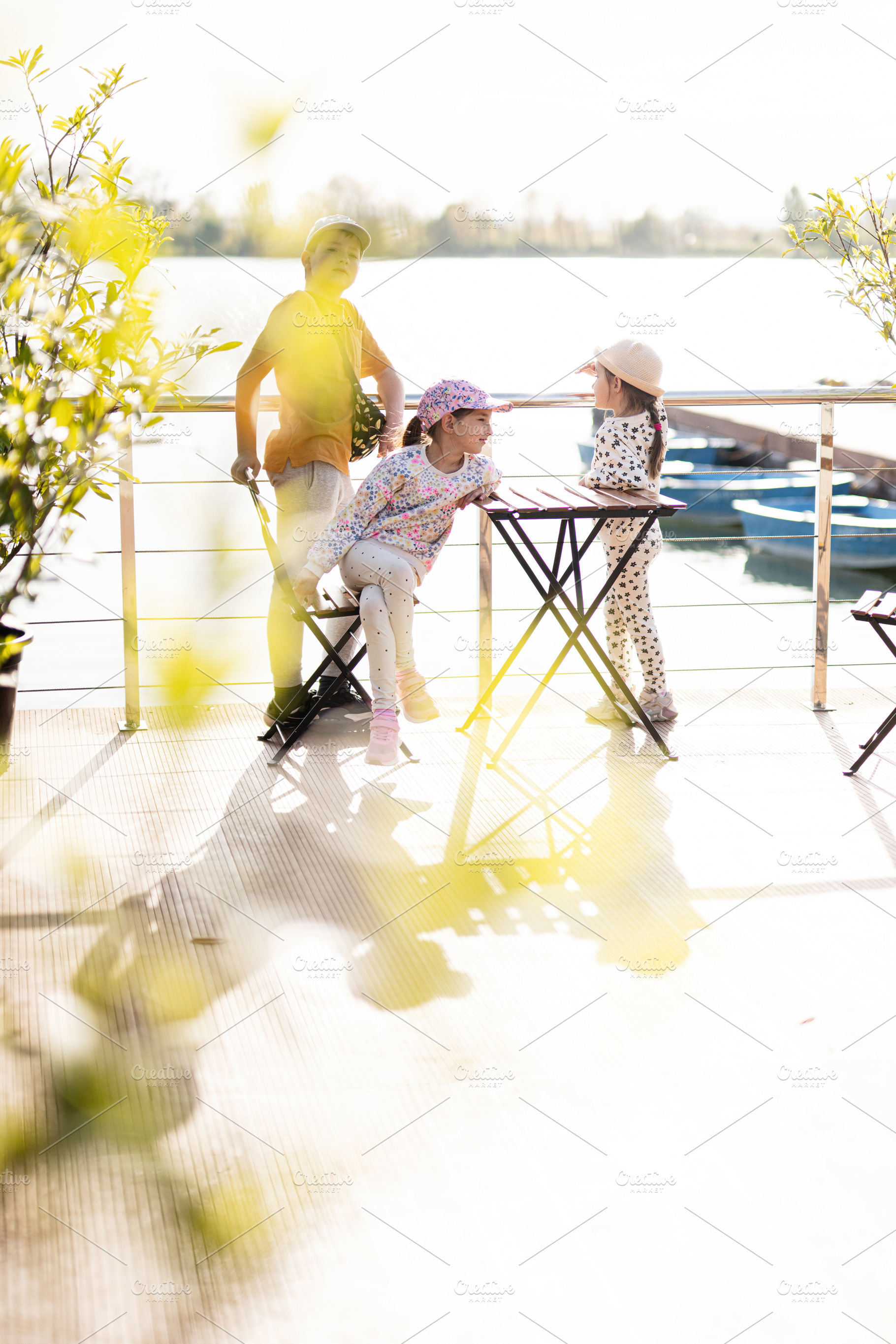 Children laughing and playing outdoors by a lake under sunny skies, a Person Photo by AS photostudio