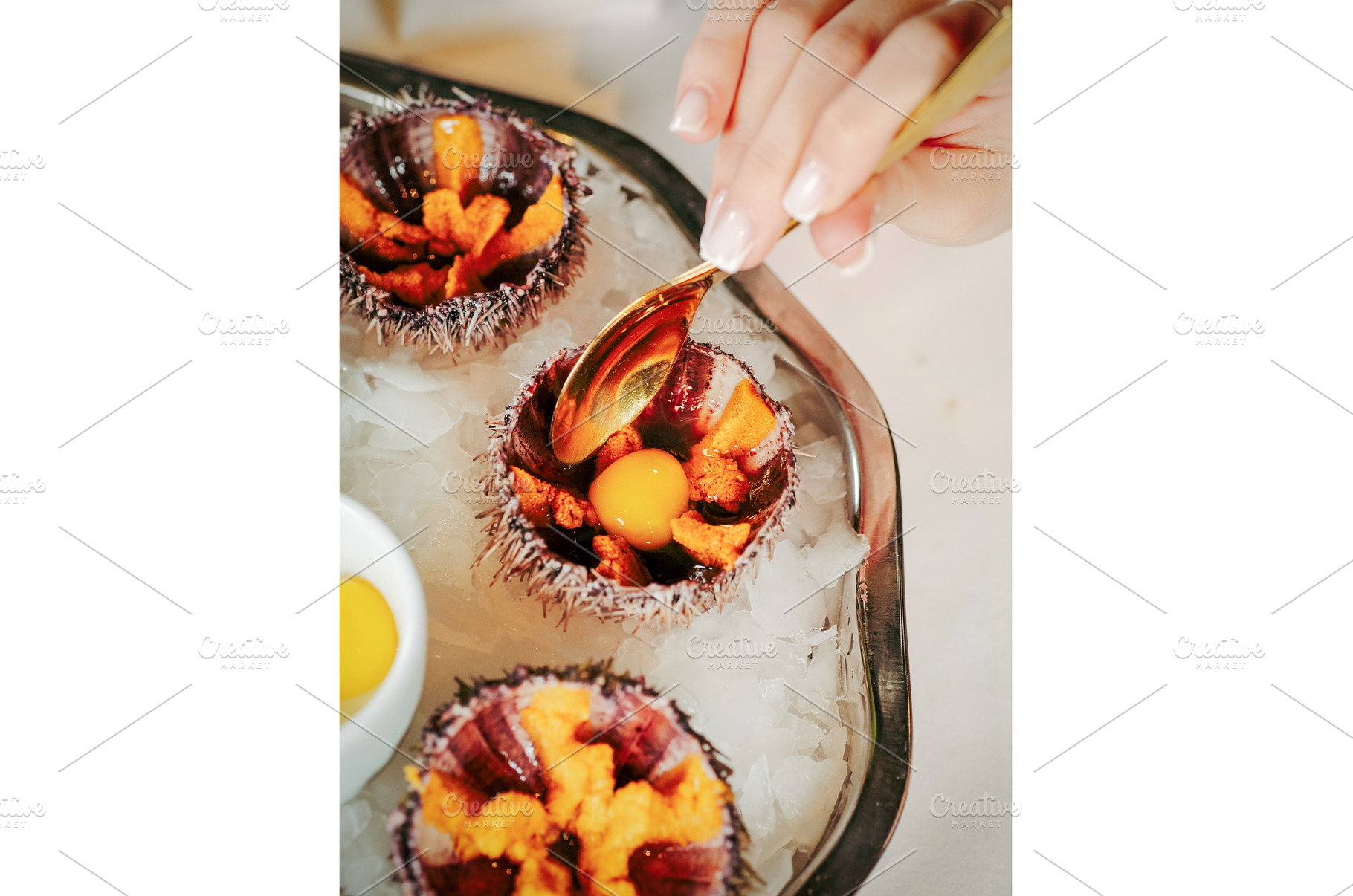 Woman having sea urchins at table, a Food & Drink Photo by Fascinadora