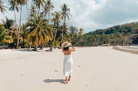 A woman in a hat enjoys the summer sun on a beautiful tropical b, a Holiday Photo by Art Rachen
