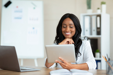 Joyful black business lady using tablet pc at workplace, speaking to colleagues, a Photo by Prostock-Studio