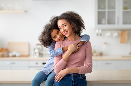 African American daughter hugging her smiling mum from the back, a Background Photo by Prostock-Studio