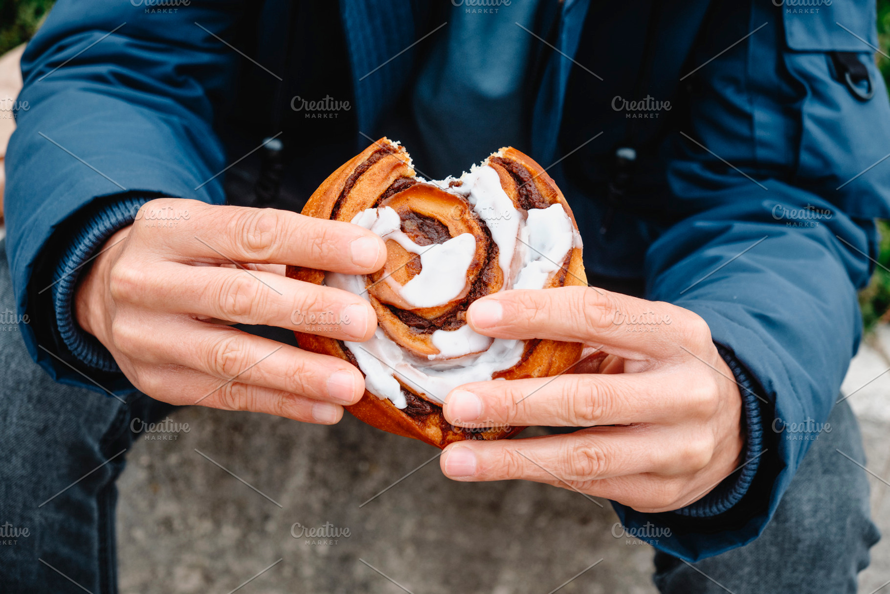 close-up of a man holding a danish kanelsnegl, a Photo by Nito