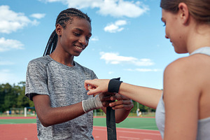 Two female runners adjusting bandages on track, a Photo by DanFLCreativo